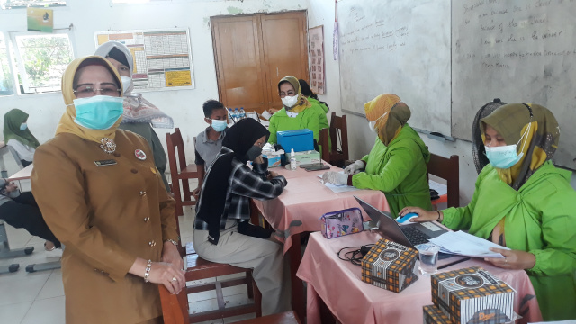 Kepala SMP N 4 Padang Eni Sugiarti menyaksikan vaksinasi massal di sekolah tersebut, Senin (11/10).